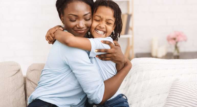 Happy black family hugging and embracing on couch