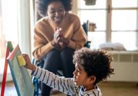 Happy black woman play and learning with little kid at home. Education children development concept
