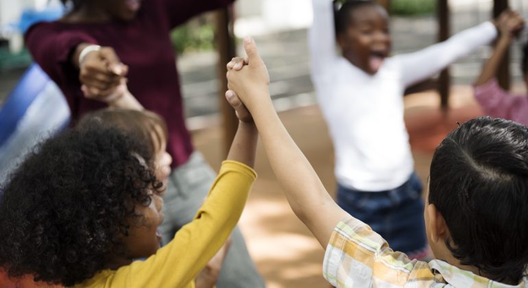 Group of diverse kindergarten students hands up together